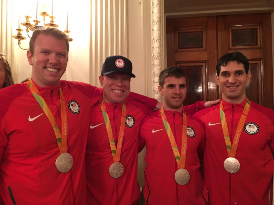 Andy Jenks, Daryl Walker, Matt Simpson and Tyler Merren wear their silver medals and matching red jackets during a visit to the White House.