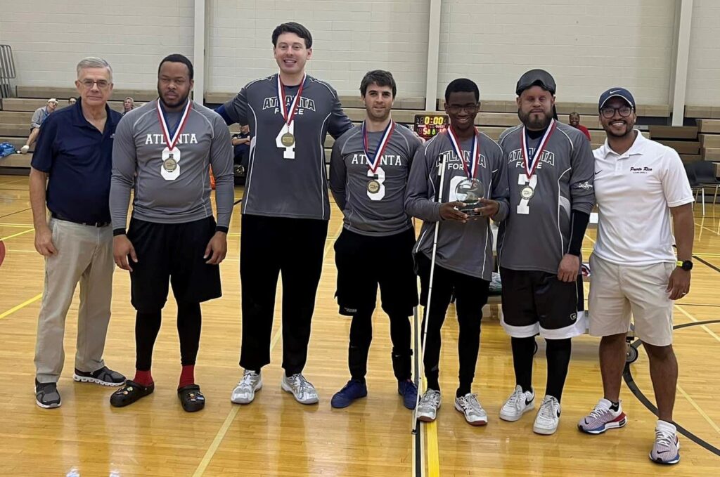 Members of the Atlanta Force men's team pose on the court with their trophy and medals.
