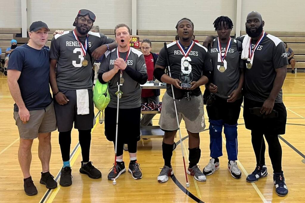 Members of the Atlanta Renegades men's team pose on the court with their trophy and medals.