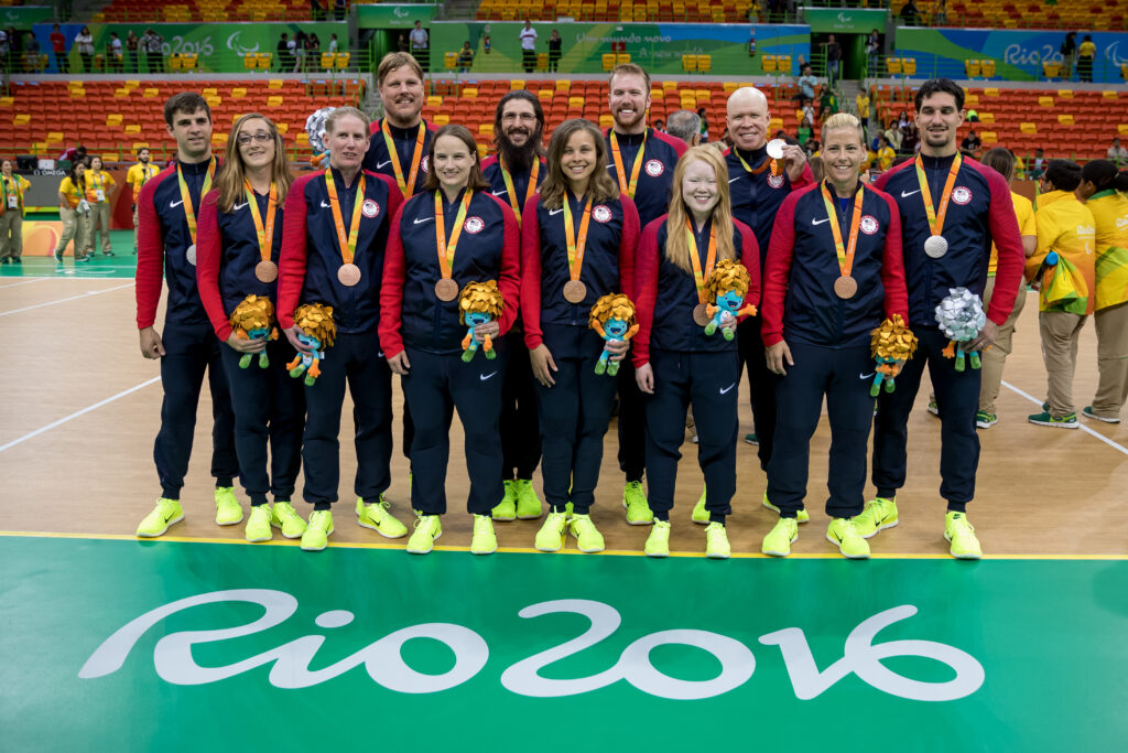The USA Goalball Men's and Women's Teams pose on the court at the Rio 2016 Paralympic Games with their medals around their necks.