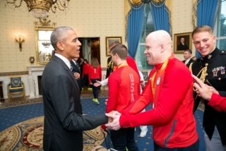 Wearing his red USA Paralympic Team jacket and his silver medal around his neck, Daryl smiles as he shakes hands with President Barack Obama inside the White House after the Rio 2016 Paralympic Games.