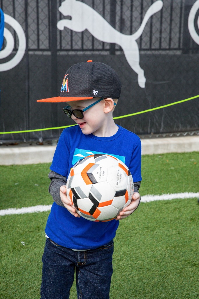 A young participant smiles as he holds a soccer ball