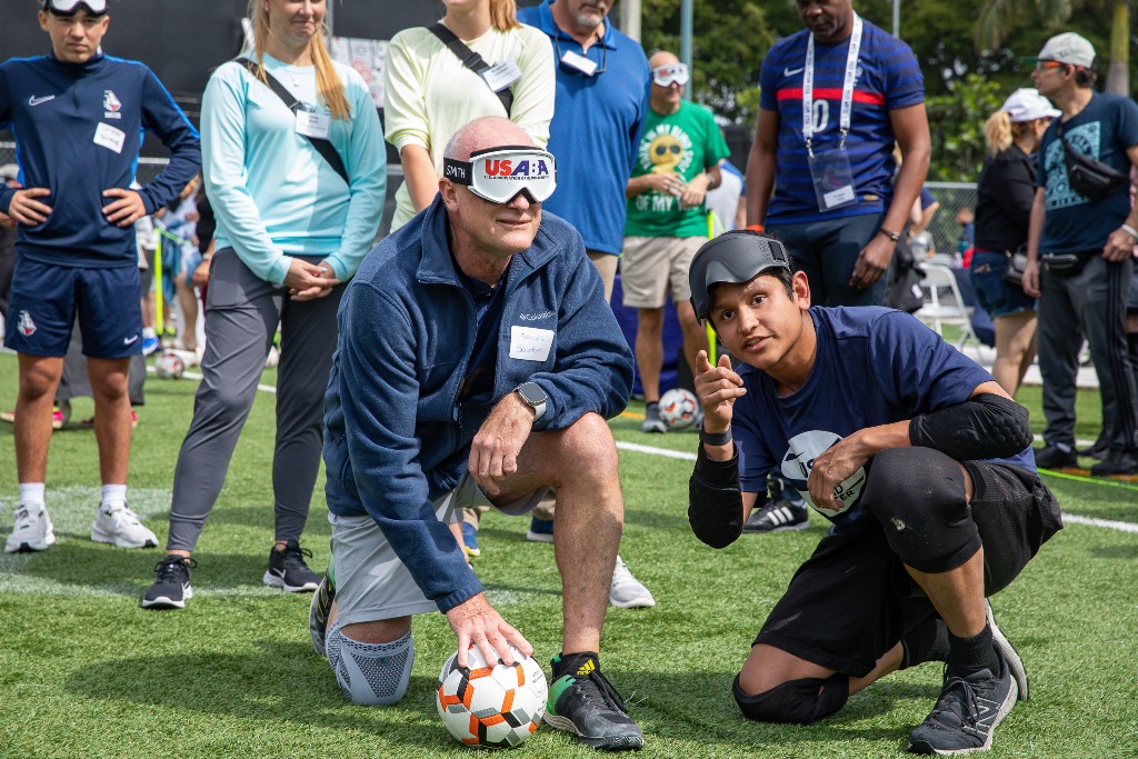 USA Blind Soccer athlete Ricky Castaneda provides instruction to a participant on how to execute a penalty kick.