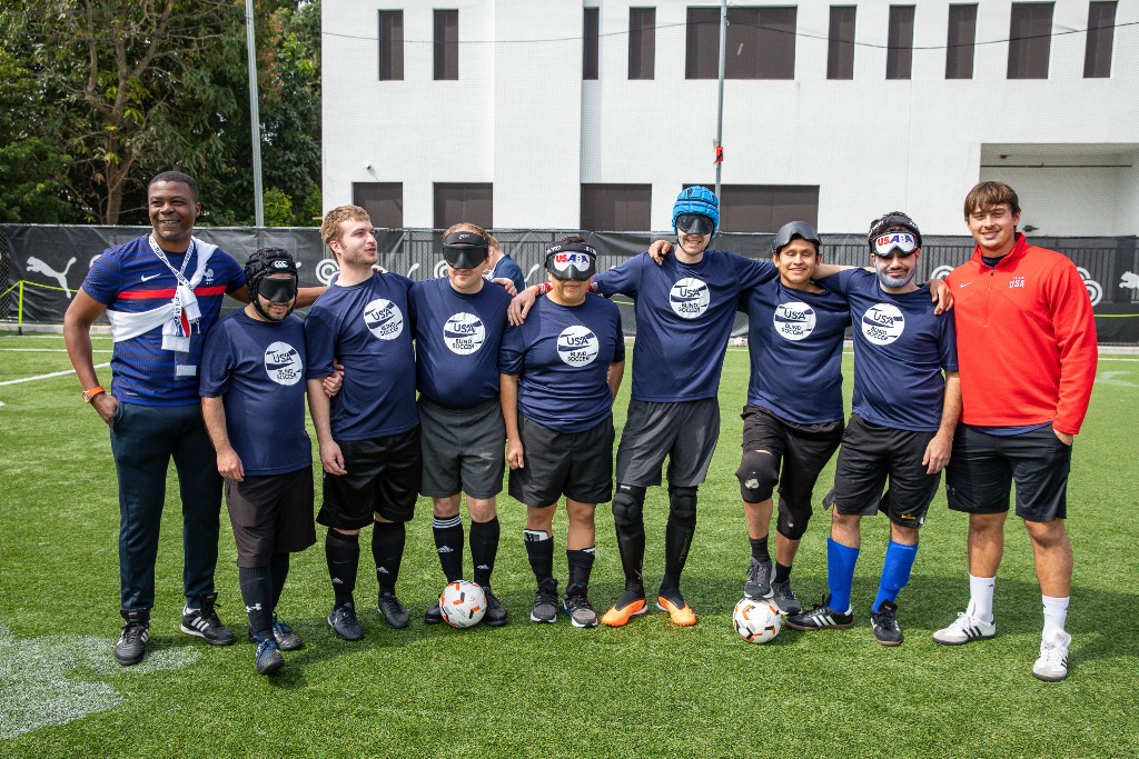 Members of the USA Blind Soccer Team pose on the field with their arms around each other following their scrimmage demonstration.
