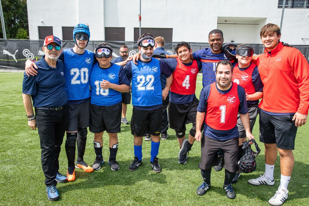 Members of the USA Blind Soccer Team pose on the field with Thomas Abraham following their scrimmage demonstration.
